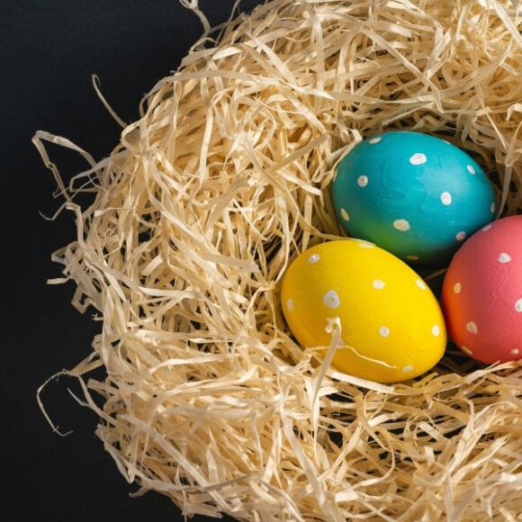 Red, yellow, and blue polka dot eggs in a straw basket