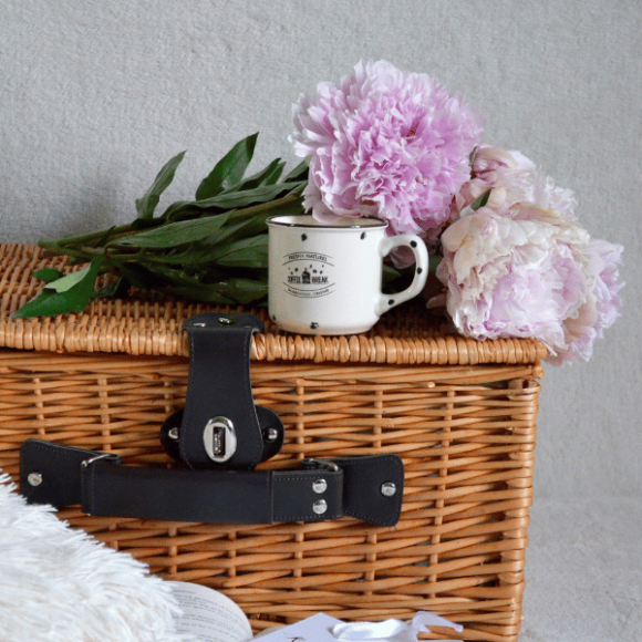A hamper with a mug and flowers on top of it