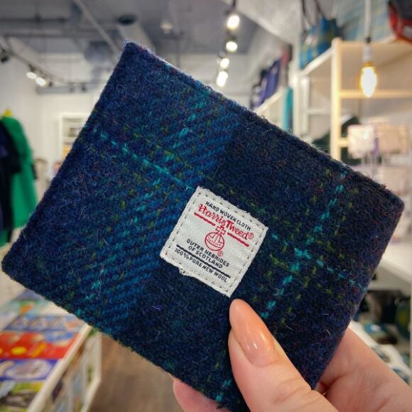 A hand holding a Harris Tweed wallet