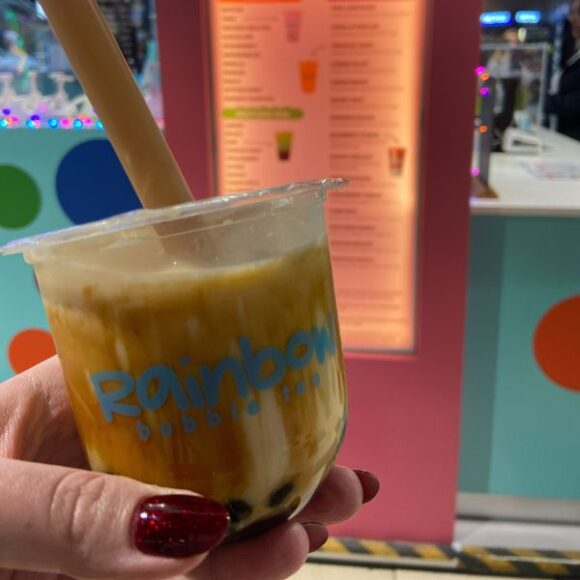 A hand holding a small bubble tea from Rainbow Bubble Tea