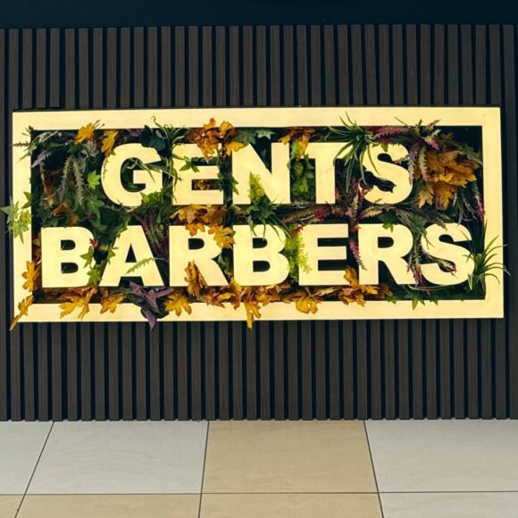 Gents Barbers in a light up sign surrounded by plants
