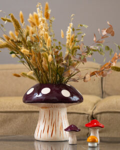 A brown toadstool shaped vase with dried flowers in it