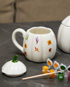 A white pumpkin shaped mug with autumnal flowers painted on it